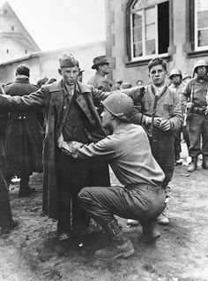 A teenager German gunner receives a pat down after surrendering to the US Army near Berlin, April 1945. Note the boy standing on the right who is wearing army boots but civilian clothing waiting his turn. Berlin, Groningen, Nederland, Antwerpen, Uithuizen, German Army