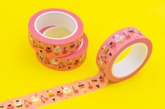 two rolls of pink washi tape sitting on top of a yellow table next to each other