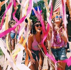 two young women standing next to each other with streamers in front of them and confetti on the ground