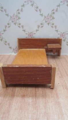 a small wooden bed sitting on top of a table next to a wallpapered wall