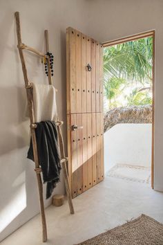 an open door leading to a bathroom with a ladder in the corner and a towel rack on the wall