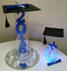 a glass vase with a toothbrush in it sitting on a table next to a graduation cap and tassel