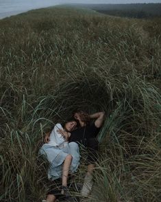 two people are laying in the tall grass