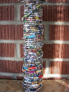 a tall stack of magazines sitting next to a brick wall