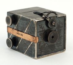 an old fashioned camera sitting on top of a white table