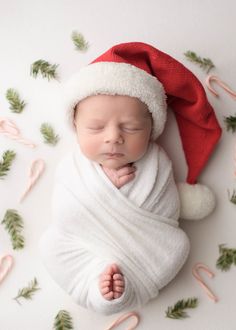 a newborn baby wrapped in a blanket and wearing a santa hat