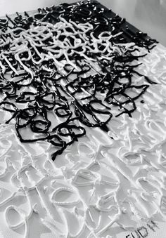 black and white photograph of scissors laying on top of a piece of paper that has been cut into smaller letters