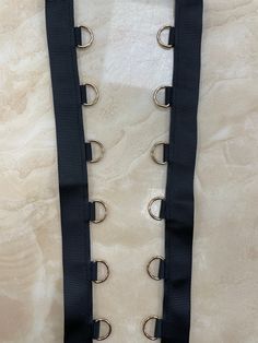 a black strap with metal rivets is on a marble surface and there are no strings attached to it