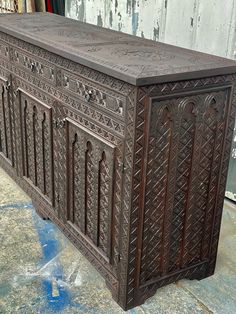 an ornately carved wooden cabinet sitting on the ground