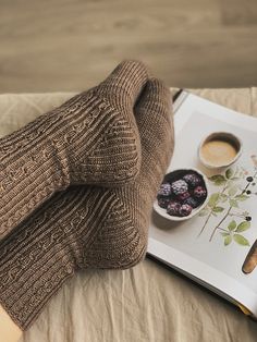 an open book with coffee and berries on it next to a pair of mittens