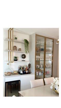 a dining room filled with lots of white furniture and glass shelves full of bottles on top of them