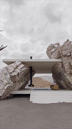 an outdoor table with rocks on it and a bench in the foreground, against a cloudy sky
