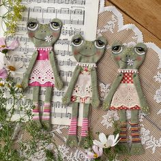 three dolls are sitting next to each other on a doily with music sheets in the background