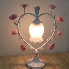 a light that is sitting on top of a table with flowers in the shape of a heart