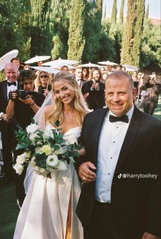 a bride and groom walking down the aisle at their outdoor wedding ceremony with guests in the background