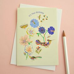 a birthday card with flowers and a bird on it next to a pencil, which reads, in your birthday