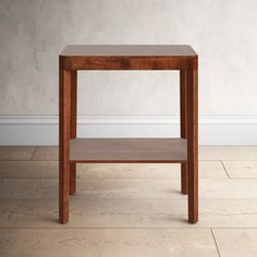 a small wooden table sitting on top of a hard wood floor next to a white wall