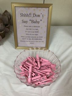pink clothes pins are in a bowl next to a sign that says, shh i don't say baby