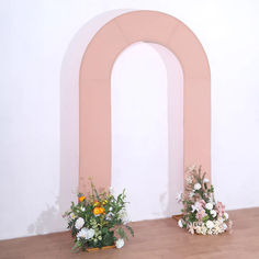 two vases filled with flowers sitting on top of a wooden floor next to an arch