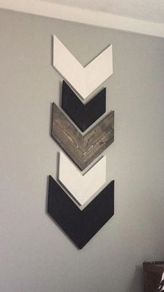 three wooden chevrons hang on the wall above a bed in a room with gray walls