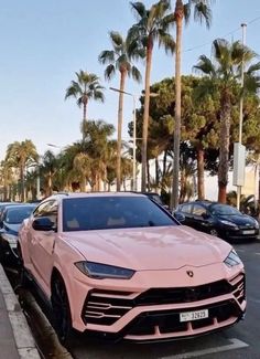 a pink sports car is parked on the side of the road in front of palm trees