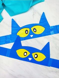 two blue and yellow paper cut outs with faces on them sitting on a marble surface