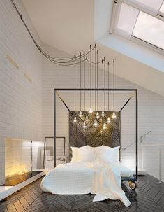 a white bed sitting under a window next to a wooden floor with lights on it