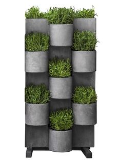 a tall metal planter filled with lots of green plants on top of each other