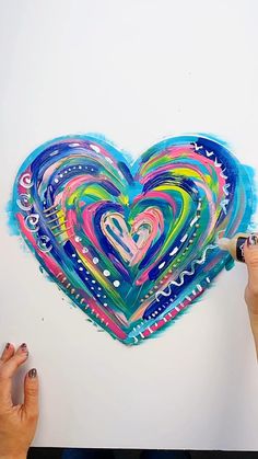 someone is drawing a colorful heart on the wall