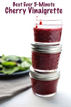 three mason jars filled with cherry jam sitting on top of a table next to a salad