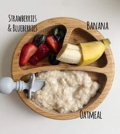a wooden plate topped with oatmeal and fruit next to a banana, strawberries, and blueberries