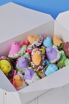 a box filled with lots of different colored candies on top of a white table