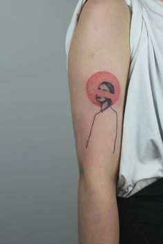a woman's arm with a pink circle tattoo on the left side of her shoulder