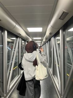 a woman walking down a walkway with a hand bag on her shoulder and headphones to her ear