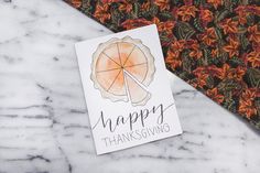 a happy thanksgiving card sitting on top of a marble table next to an orange tie