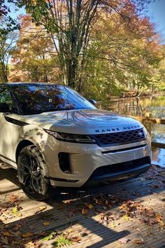 a white range rover parked in front of a lake