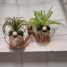 two planters with plants in them on a mantle