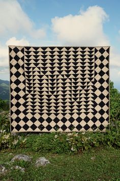 a black and white quilt sitting on top of a lush green field