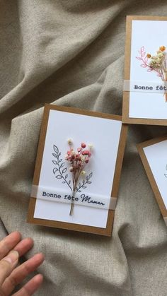three greeting cards with flowers on them are being held by someone who is holding the card