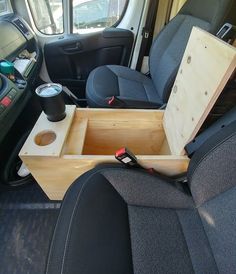 the interior of a van with an open drawer in the back seat and cup holders on the side