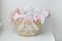a pink bunny sitting in a basket next to a greeting card and some other items