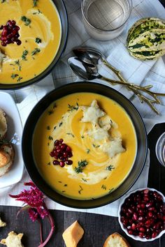 two bowls filled with soup next to bread and cranberries