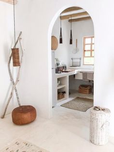 an archway leading into a bathroom with white walls and flooring, along with a wooden stool