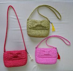 three crocheted purses sitting on top of a white table next to each other