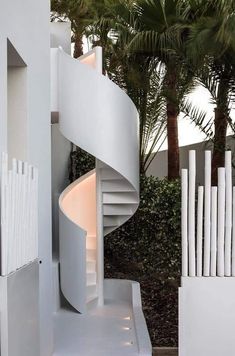 a white spiral staircase next to palm trees
