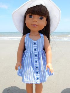a doll is standing on the beach wearing a hat