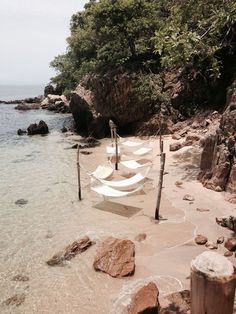there are several boats that are tied to the rocks on the beach by the water