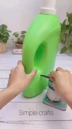 a person is cutting out the outline for a green plastic container with scissors and thread