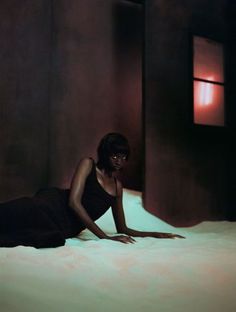 a woman in a black dress laying on a bed