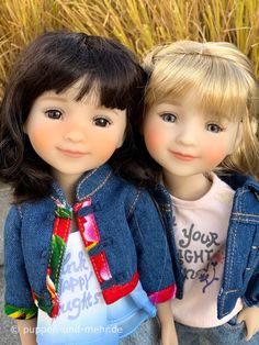 two dolls are sitting next to each other on the ground in front of some tall grass